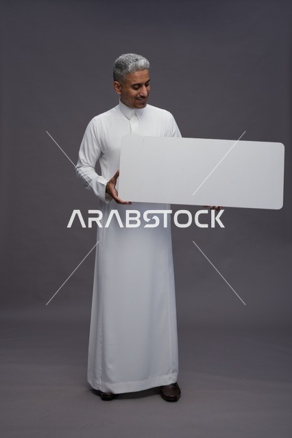 رجل سعودي يمسك لوحة إعلانية بيضاء فارغة