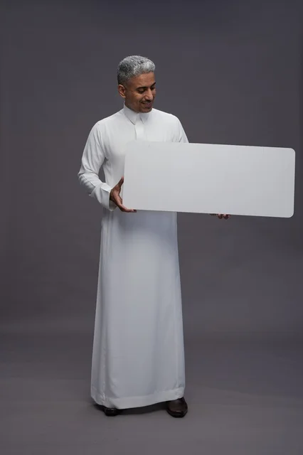 رجل سعودي يمسك لوحة إعلانية بيضاء فارغة