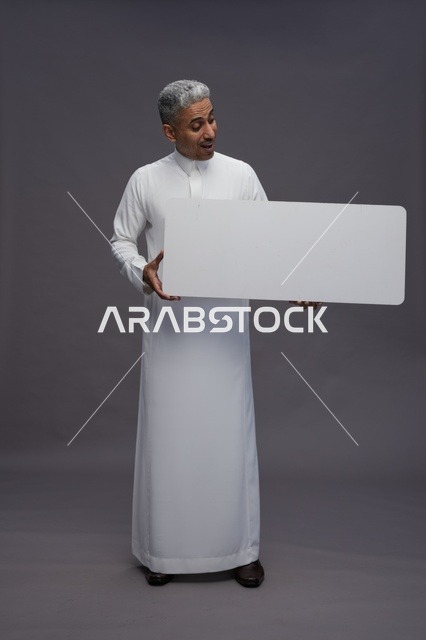 رجل سعودي يحمل لوحة بيضاء فارغة في الاستوديو