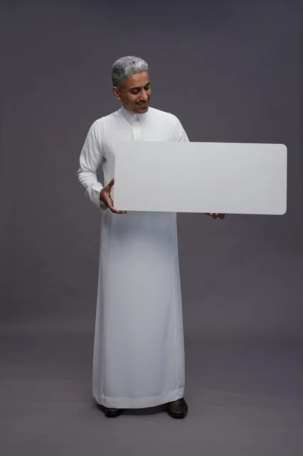 رجل سعودي بالثوب التقليدي يحمل لوحة بيضاء فارغة