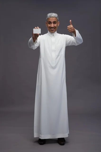 رجل سعودي بالثوب يحمل بطاقة فارغة في الاستوديو