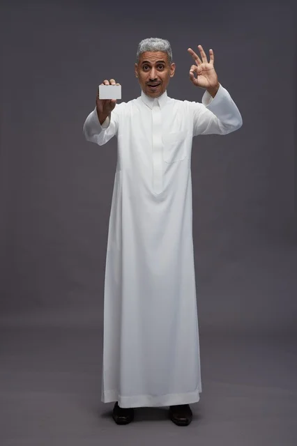 رجل سعودي بالثوب الأبيض يحمل بطاقة بيضاء فارغة