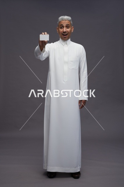 رجل سعودي بالثوب الأبيض يمسك بطاقة فارغة بتعبير مندهش