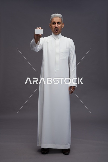 رجل سعودي مندهش يحمل بطاقة عمل بيضاء فارغة