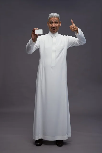 رجل سعودي في الاستوديو يحمل بطاقة عمل فارغة