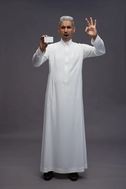 رجل سعودي يمسك بطاقة فارغة مع إيماءة موافقة