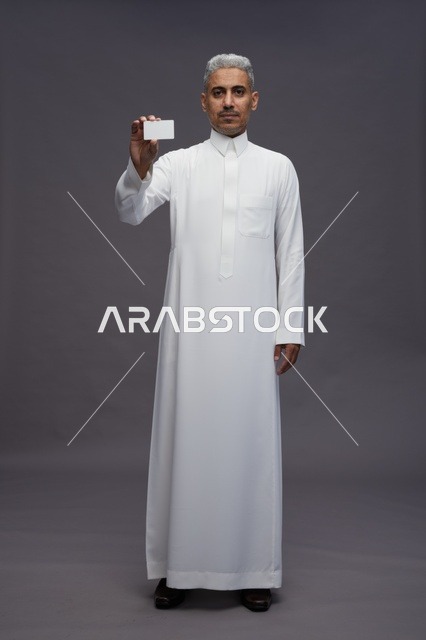 رجل سعودي يحمل بطاقة عمل فارغة في الاستوديو