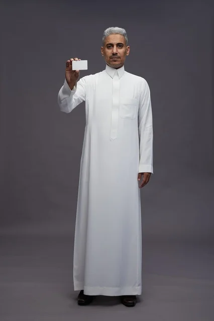 رجل سعودي يحمل بطاقة عمل فارغة في الاستوديو