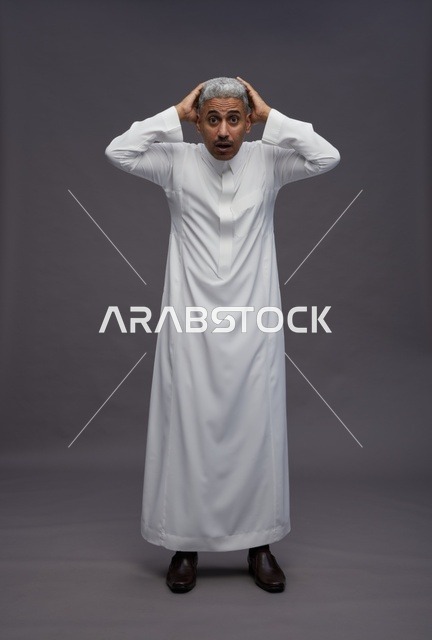 رجل سعودي مصدوم يرتدي الثوب الأبيض بخلفية رمادية