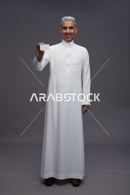 رجل سعودي يحمل بطاقة عمل فارغة في الاستوديو