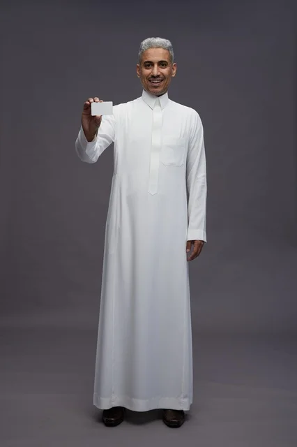 رجل سعودي يحمل بطاقة عمل فارغة في الاستوديو