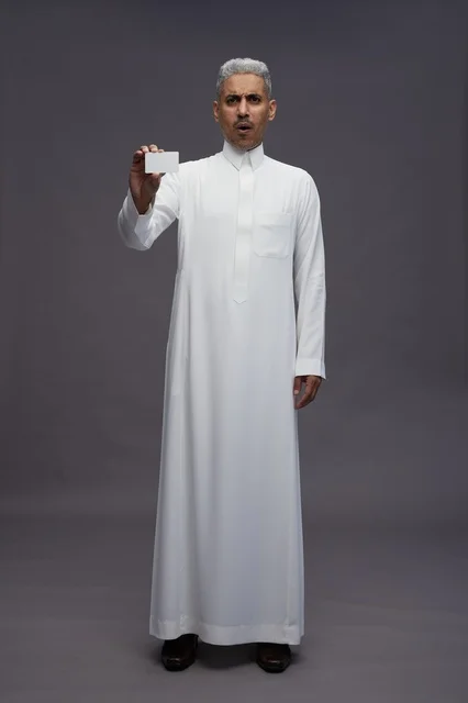 رجل سعودي بالثوب يمسك بطاقة عمل فارغة