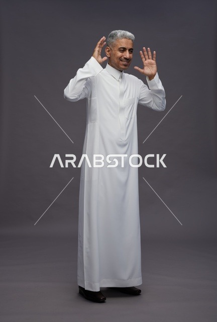 Arab Man in White Thobe Raising Hands on Grey Background