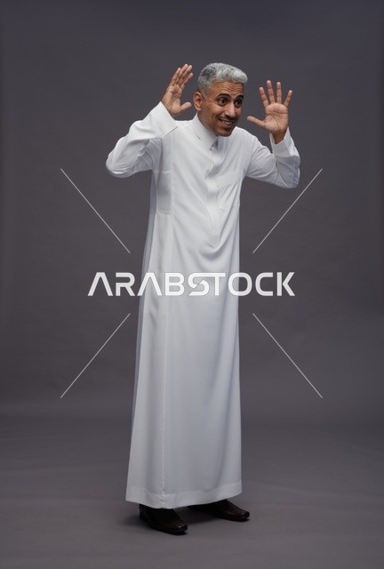 رجل سعودي بالثوب الأبيض يرفع يديه في الاستوديو