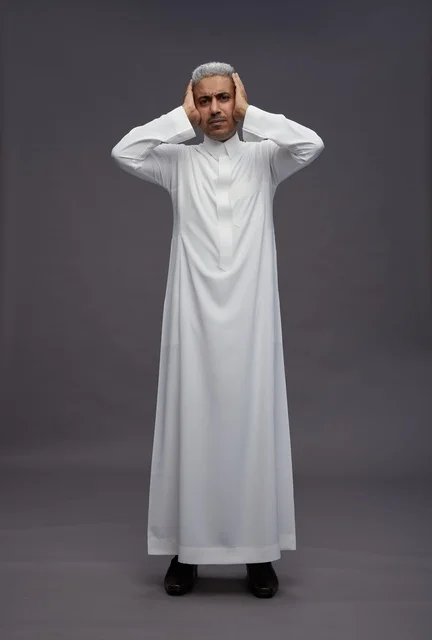 رجل سعودي بالثوب الأبيض يغطي أذنيه خلفية رمادية