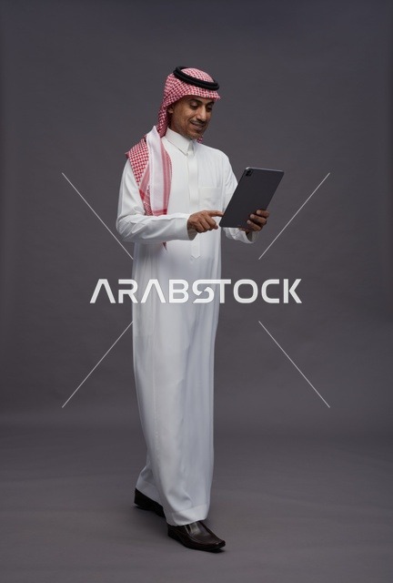 Saudi Man in Traditional Thobe Using a Digital Tablet