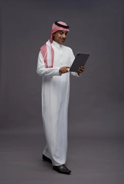 Saudi Man in Traditional Thobe Using a Digital Tablet