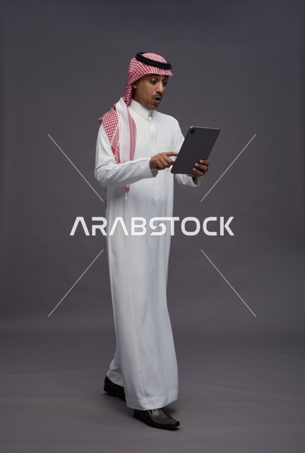 Saudi Man Using Digital Tablet on Grey Background