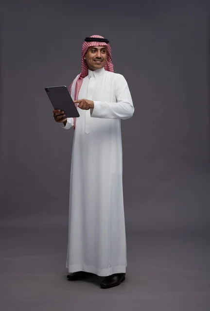 رجل سعودي يستخدم جهازاً لوحياً بخلفية رمادية