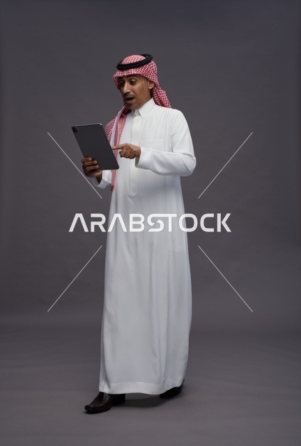 رجل سعودي يستخدم جهاز لوحي بتعبير وجه مندهش