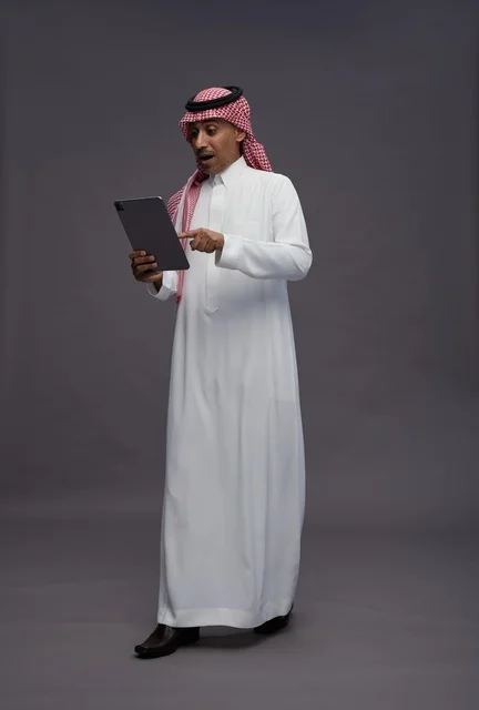 رجل سعودي يستخدم جهاز لوحي بتعبير وجه مندهش