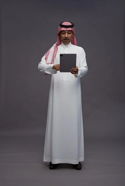 رجل سعودي مع جهاز لوحي بتعبير مندهش تصوير استوديو