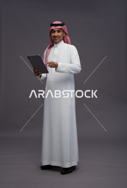 Saudi Man in Traditional Thobe Holding Digital Tablet
