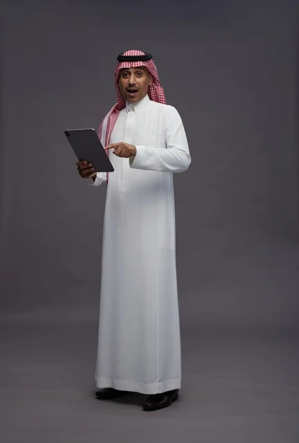 Surprised Saudi Man with Tablet on Grey Background
