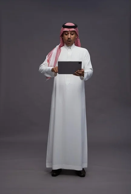 Surprised Saudi Man Using Tablet on Grey Background