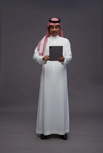 Saudi Man in Traditional Thobe Using Digital Tablet