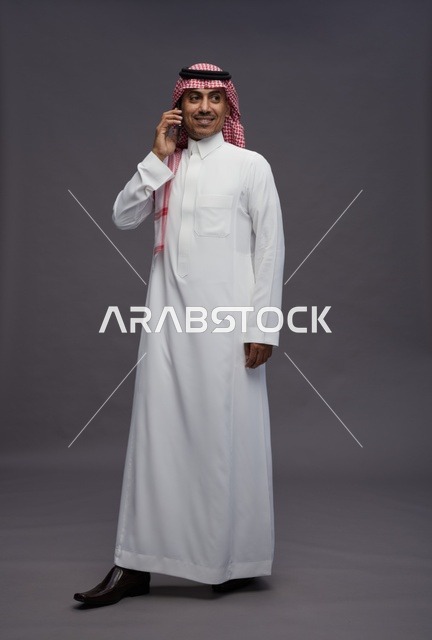 Saudi Man in Traditional Thobe Using Smartphone