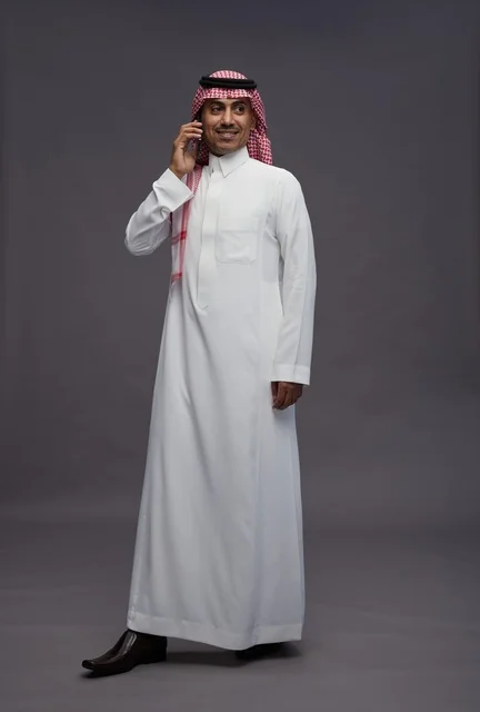 رجل سعودي بالثوب التقليدي يستخدم الهاتف الذكي