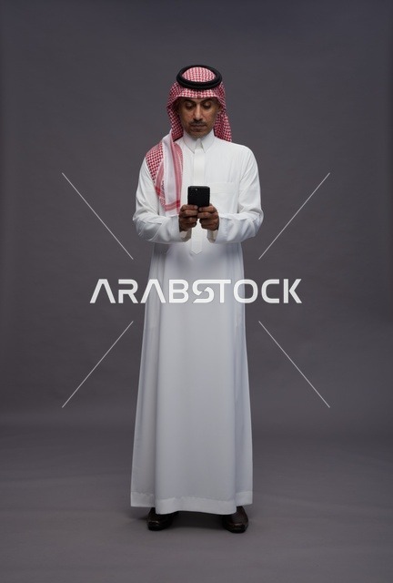 Saudi Man in Traditional Thobe Using Smartphone