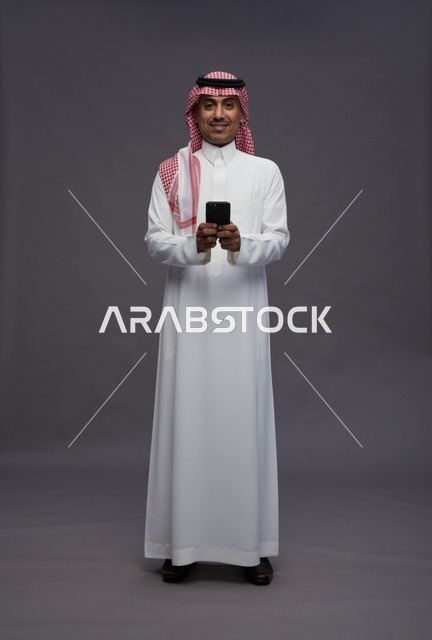 Saudi Man in Traditional Dress with Smartphone