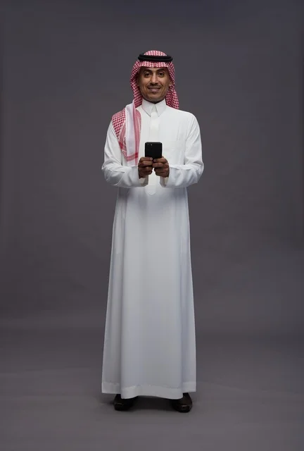 Saudi Man in Traditional Dress with Smartphone