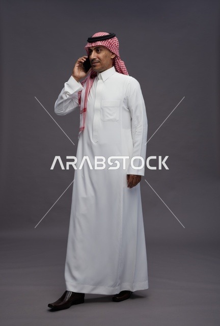 رجل سعودي بالزي التقليدي يتحدث عبر الهاتف الجوال