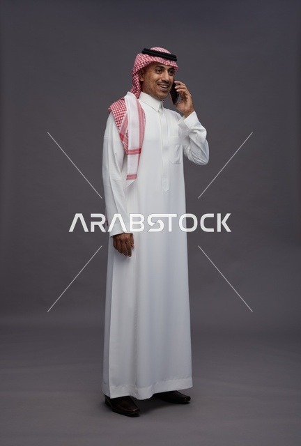 رجل سعودي بالزي التقليدي يستخدم الهاتف الذكي