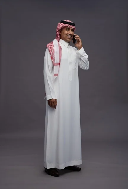 رجل سعودي بالزي التقليدي يستخدم الهاتف الذكي