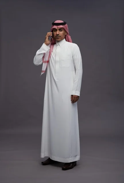 رجل سعودي بالزي التقليدي يتحدث عبر الهاتف المحمول