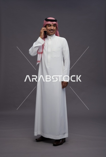رجل سعودي بالزي التقليدي يتحدث عبر الهاتف المحمول