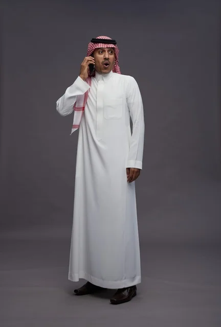 رجل سعودي متفاجئ يتحدث بالهاتف المحمول في الاستوديو