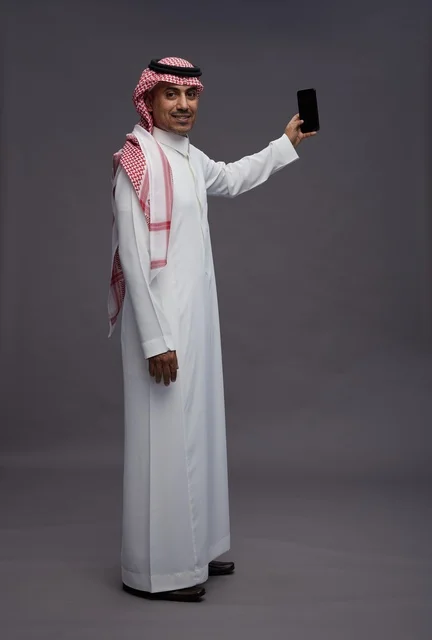 Saudi Man in Traditional Thobe Holding Smartphone