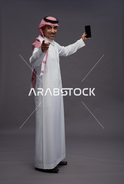 Saudi Man Holding Smartphone on Grey Background