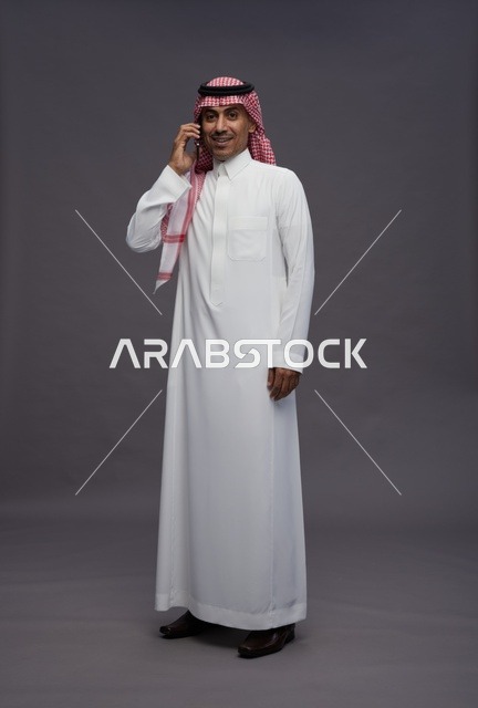 Saudi Man in Traditional Thobe Using Smartphone in Studio