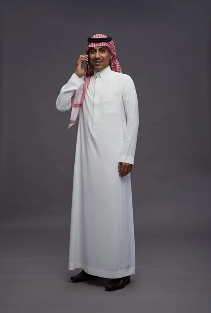 رجل سعودي بالثوب التقليدي يستخدم الهاتف في الاستوديو