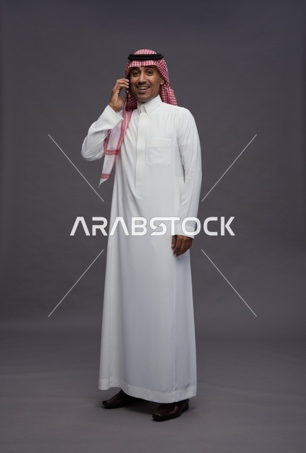 رجل سعودي بالثوب يتحدث في الهاتف الذكي