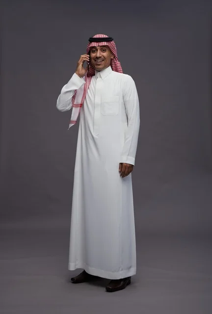 رجل سعودي بالثوب يتحدث في الهاتف الذكي