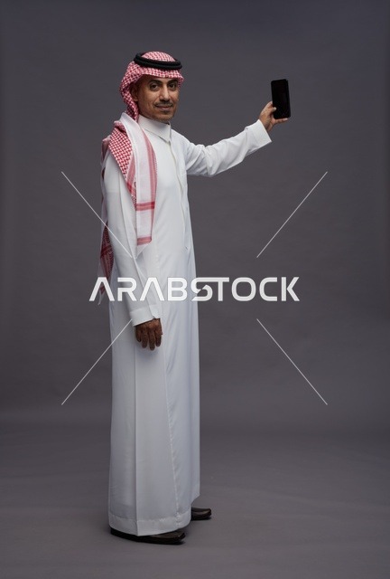 Saudi Man in Traditional Thobe Holding Smartphone
