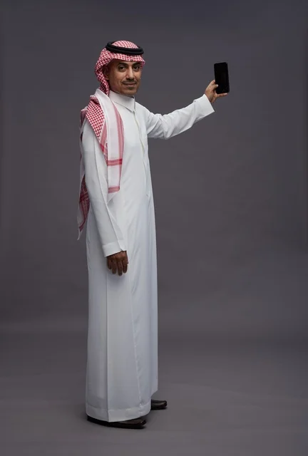 Saudi Man in Traditional Thobe Holding Smartphone