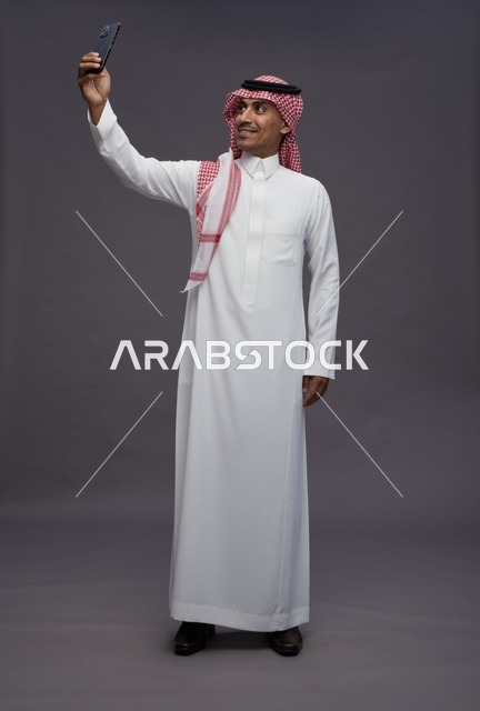 Saudi Man in Traditional Thobe Taking Smartphone Selfie